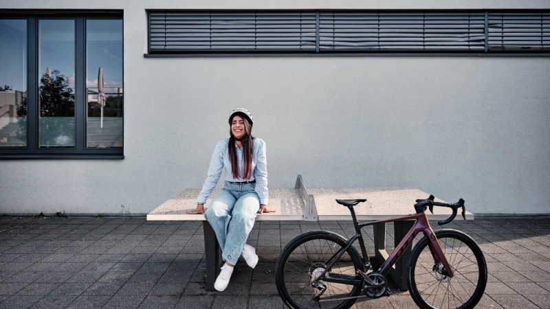 Eine Frau sitzt auf einer Tischtennisplatte, ihr Gravelbike steht neben ihr